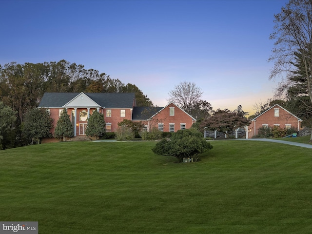 neoclassical / greek revival house featuring brick siding and a front yard