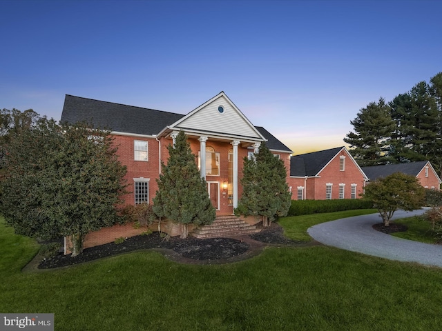 greek revival house featuring brick siding and a front lawn