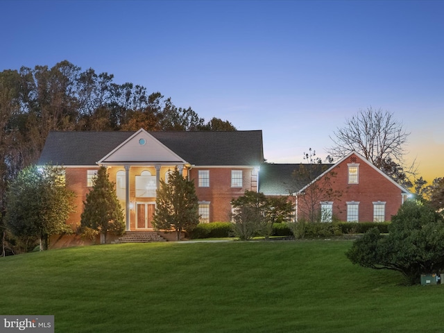 view of front facade with a yard and brick siding