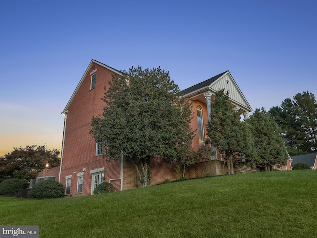 view of property exterior with brick siding and a lawn