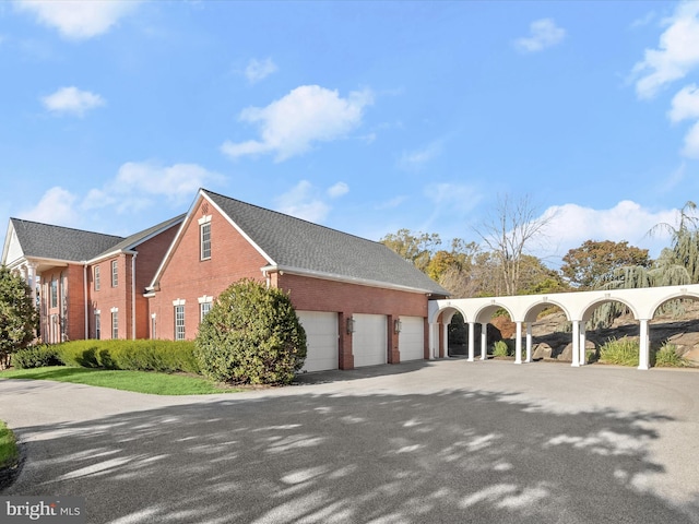 view of property exterior with brick siding, driveway, and a shingled roof