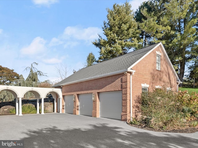 view of property exterior featuring aphalt driveway, brick siding, an attached garage, and a shingled roof