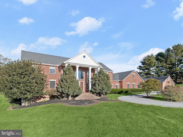 greek revival inspired property featuring brick siding and a front yard