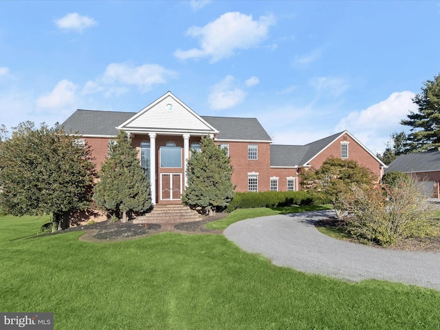 greek revival house featuring brick siding and a front lawn