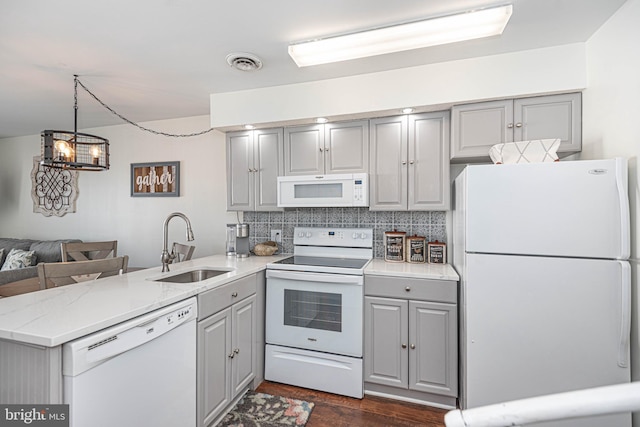 kitchen with a sink, white appliances, gray cabinets, a peninsula, and visible vents