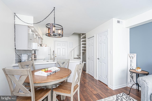 dining room with dark wood finished floors, stairway, visible vents, baseboards, and a chandelier