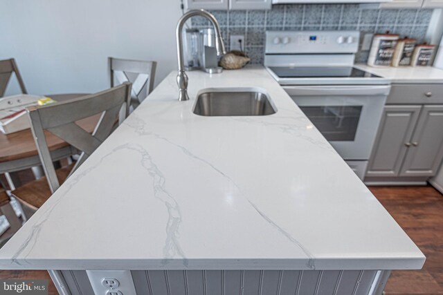 kitchen featuring a sink, gray cabinetry, light stone countertops, white range with electric cooktop, and dark wood-type flooring