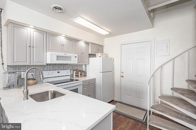 kitchen featuring decorative backsplash, white appliances, light stone counters, and gray cabinetry