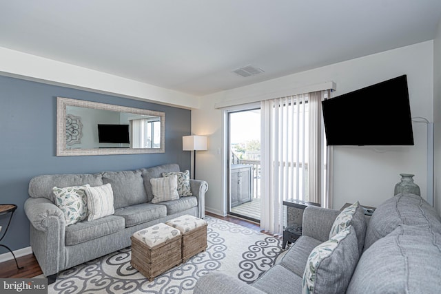 living area with baseboards, wood finished floors, and visible vents