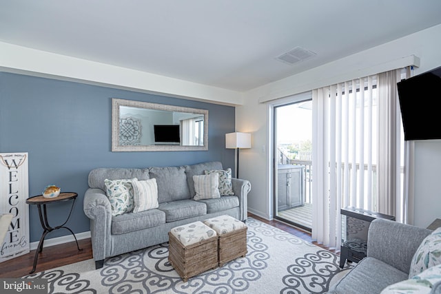 living area with baseboards, wood finished floors, and visible vents