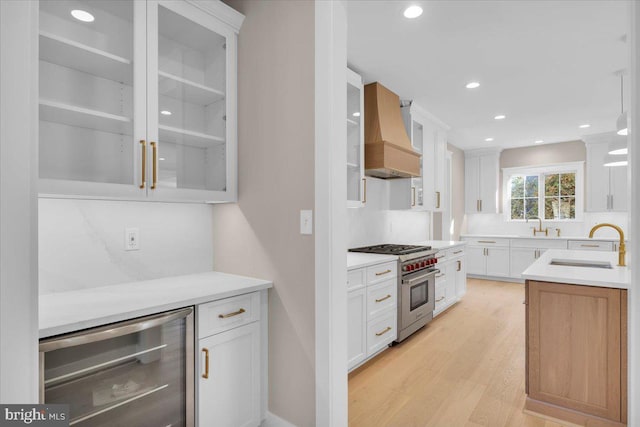 kitchen with white cabinets, custom exhaust hood, luxury range, and beverage cooler