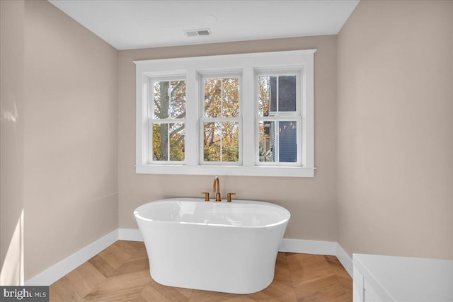 bathroom featuring parquet flooring and a bath