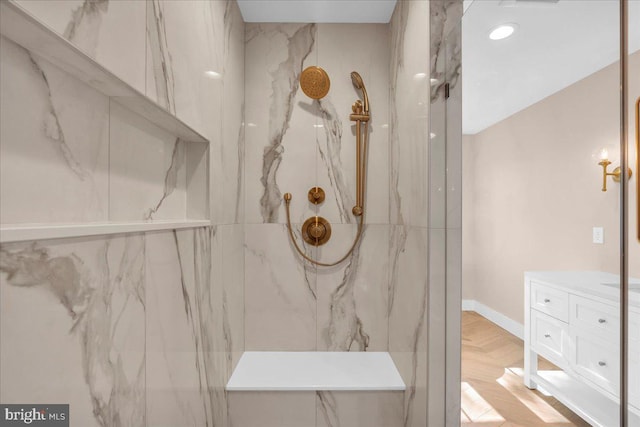 bathroom featuring a tile shower, vanity, and parquet flooring