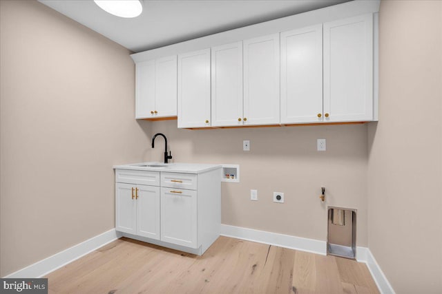 clothes washing area with cabinets, sink, light hardwood / wood-style flooring, washer hookup, and hookup for an electric dryer