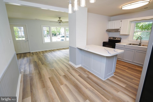 kitchen featuring plenty of natural light, pendant lighting, white cabinets, and electric range