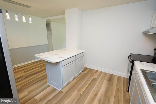 kitchen with light wood-type flooring, white cabinetry, pendant lighting, light stone countertops, and electric range