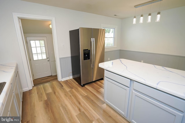 kitchen featuring light hardwood / wood-style floors, light stone counters, stainless steel refrigerator with ice dispenser, decorative light fixtures, and white cabinets