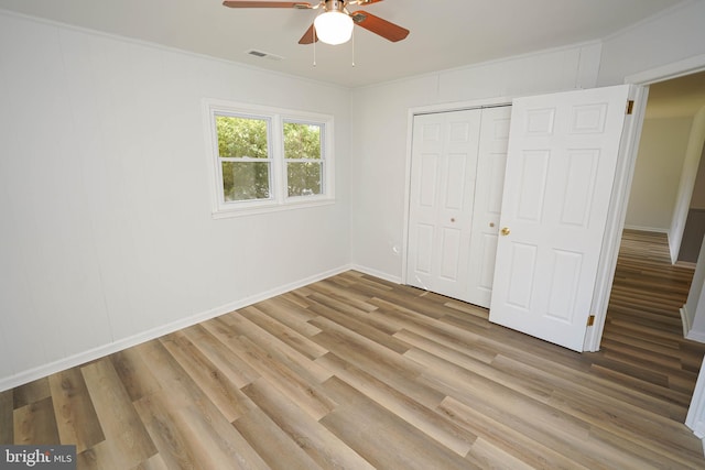 unfurnished bedroom with ornamental molding, hardwood / wood-style flooring, ceiling fan, and a closet