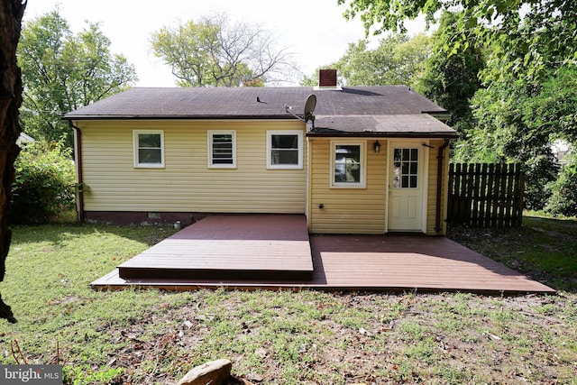 rear view of house featuring a wooden deck and a lawn