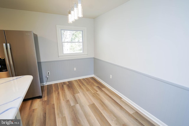 unfurnished dining area with light hardwood / wood-style floors and an inviting chandelier