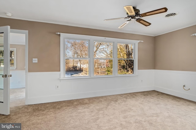 empty room with light carpet, crown molding, french doors, and ceiling fan