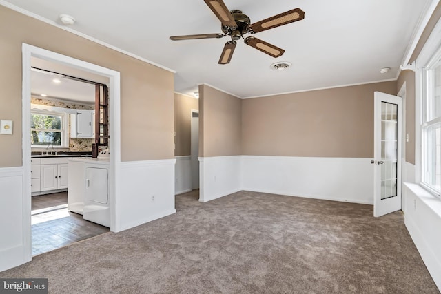 empty room featuring crown molding, sink, and dark carpet