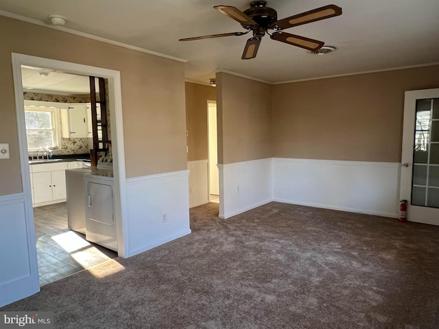 carpeted empty room featuring separate washer and dryer, sink, crown molding, and ceiling fan