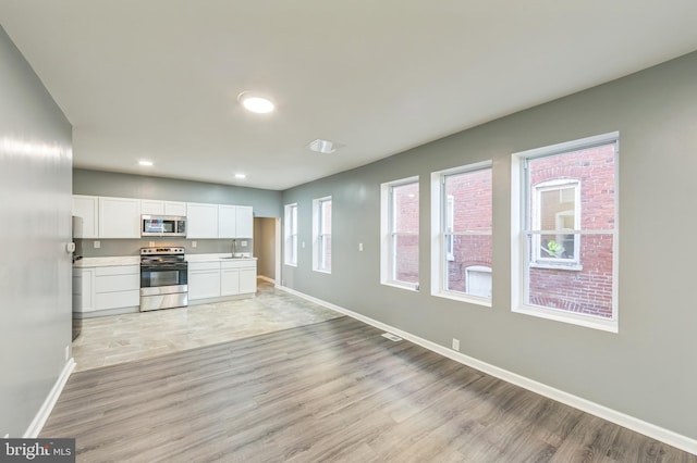 kitchen featuring appliances with stainless steel finishes, white cabinetry, sink, and light wood-type flooring