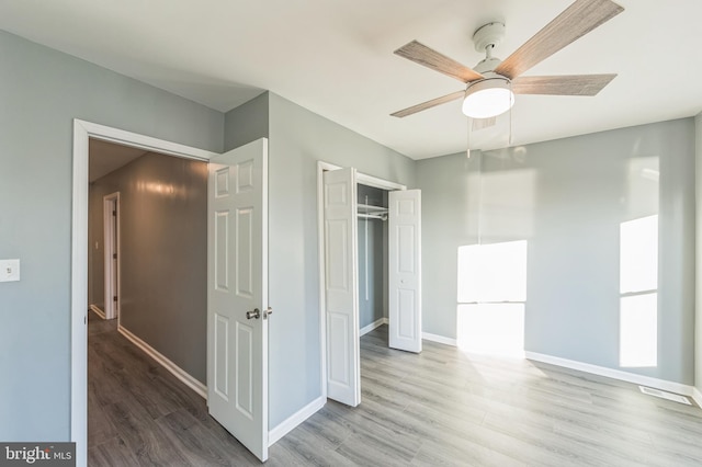 unfurnished bedroom featuring a closet, wood-type flooring, and ceiling fan