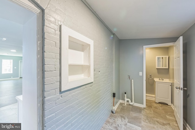 laundry room with brick wall, sink, and built in shelves