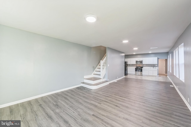 unfurnished living room featuring sink and light wood-type flooring