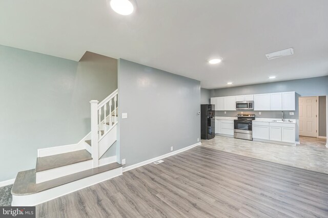 kitchen featuring light hardwood / wood-style floors, stainless steel appliances, sink, and white cabinets