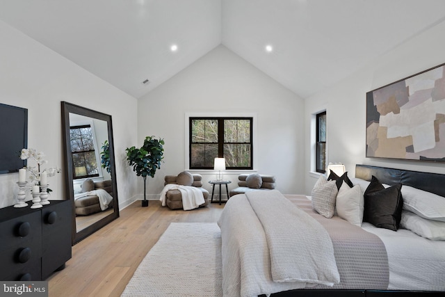 bedroom featuring high vaulted ceiling and light hardwood / wood-style flooring