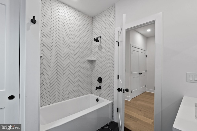 bathroom with hardwood / wood-style floors and tiled shower / bath