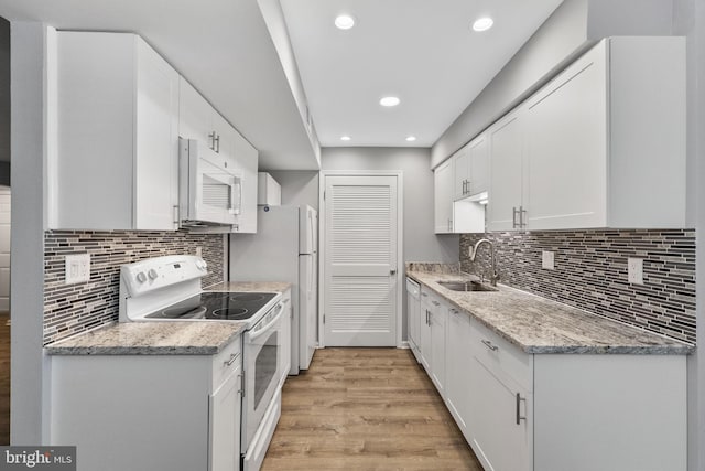 kitchen featuring white cabinetry, sink, light stone counters, white appliances, and light wood-type flooring