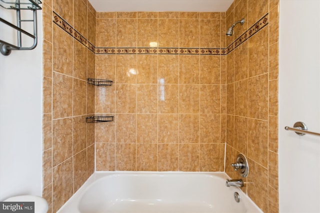 bathroom with toilet and tiled shower / bath