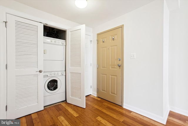 clothes washing area featuring stacked washer and clothes dryer and hardwood / wood-style flooring