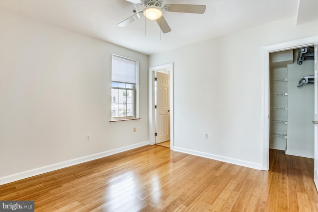 unfurnished bedroom with light hardwood / wood-style flooring, ceiling fan, a walk in closet, and a closet