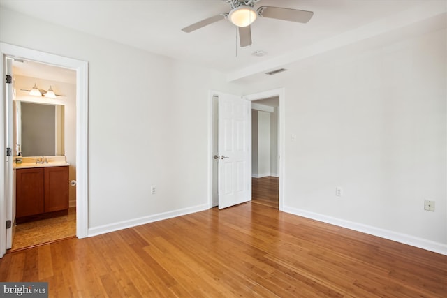 unfurnished bedroom featuring ensuite bathroom, light hardwood / wood-style floors, sink, and ceiling fan