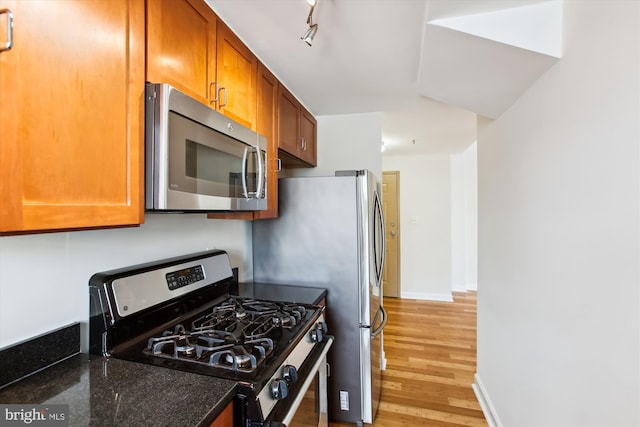 kitchen with light wood-type flooring, black gas range oven, and dark stone countertops