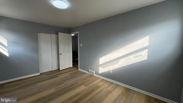 unfurnished bedroom with wood-type flooring and a closet