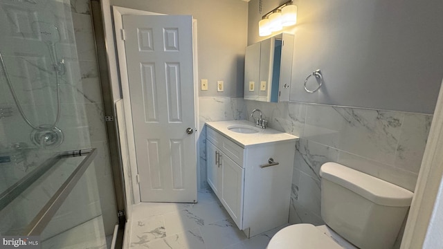 bathroom with tile walls, vanity, toilet, and a shower with door