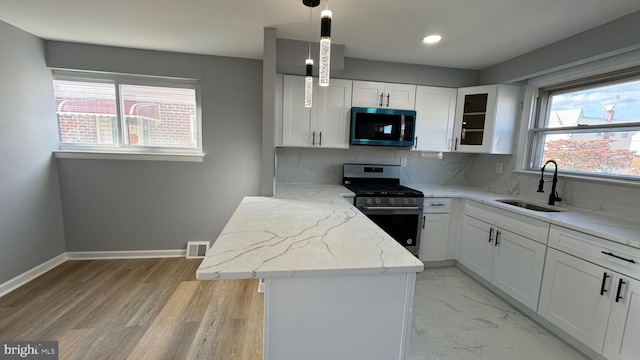 kitchen with appliances with stainless steel finishes, hanging light fixtures, a healthy amount of sunlight, and sink