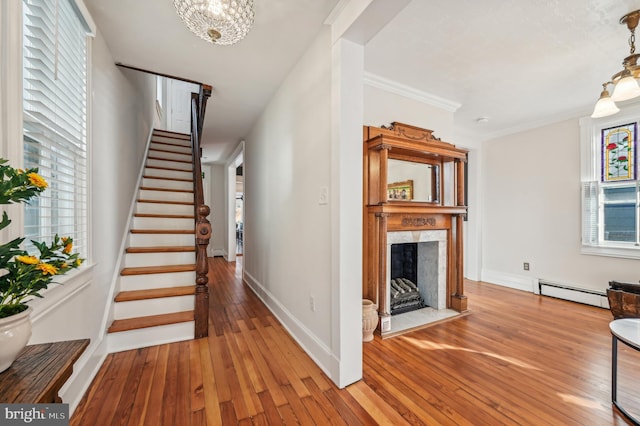 stairs with wood-type flooring, a baseboard radiator, and a healthy amount of sunlight