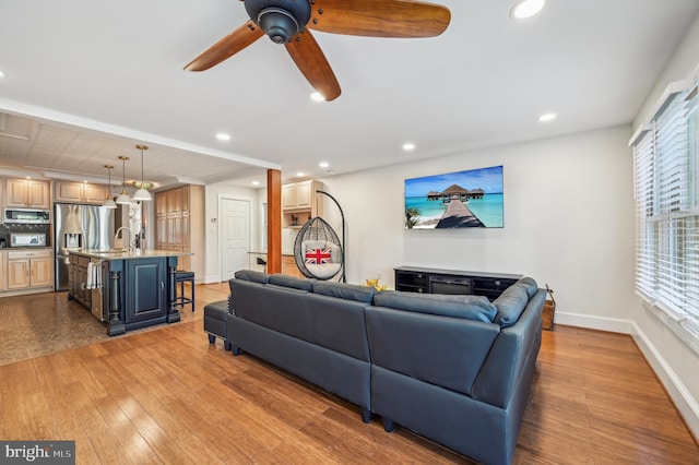 living room featuring ceiling fan, hardwood / wood-style floors, and sink