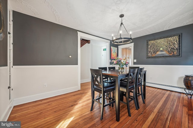 dining room featuring a chandelier, wood-type flooring, a textured ceiling, and baseboard heating