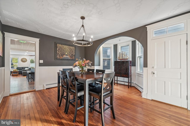 dining area featuring a chandelier, wood-type flooring, and a baseboard heating unit