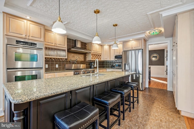 kitchen with wood-type flooring, appliances with stainless steel finishes, a breakfast bar area, and wall chimney range hood