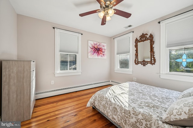 bedroom featuring wood-type flooring, ceiling fan, and a baseboard heating unit