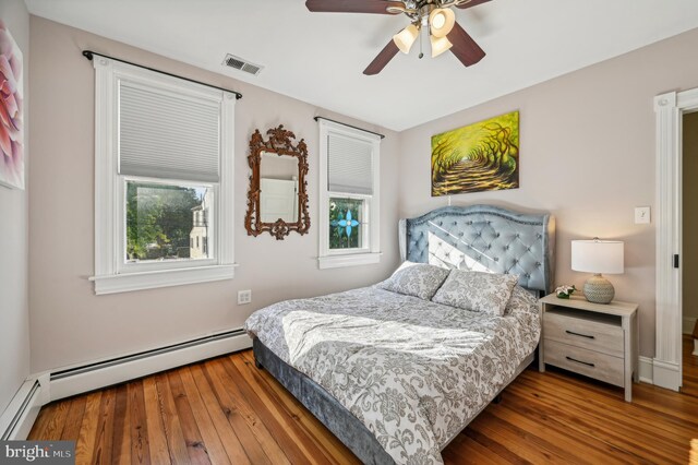 bedroom with hardwood / wood-style flooring, a baseboard radiator, and ceiling fan